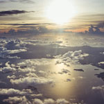 aerial view of land and sea through clouds at sunset